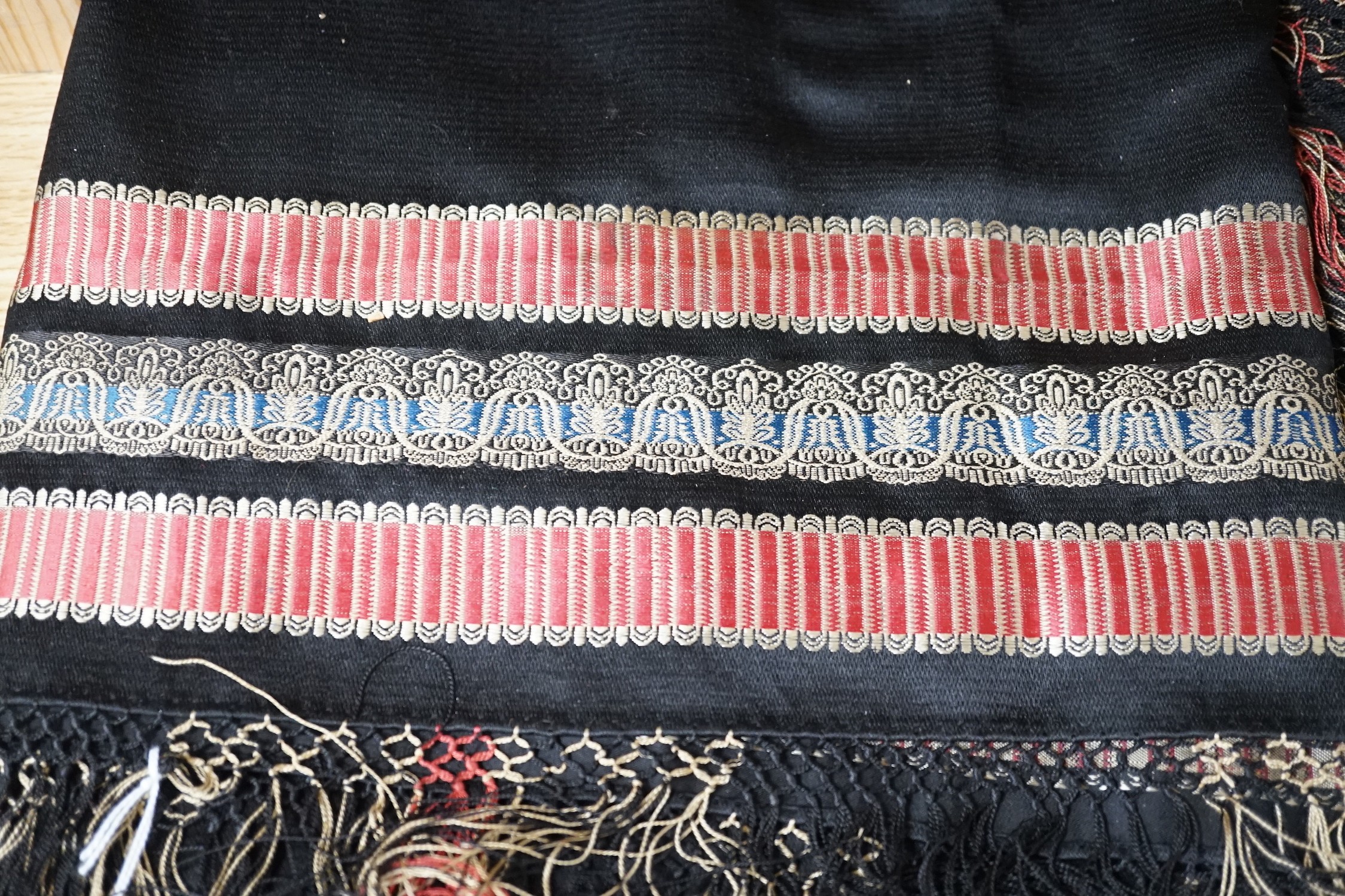 A Victorian black silk shawl woven, woven with multi-coloured Paisley designed stripes bordered with a silk multi-coloured fringe, 184cms square (not including fringe)